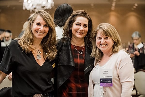 Three women smiling at an event.