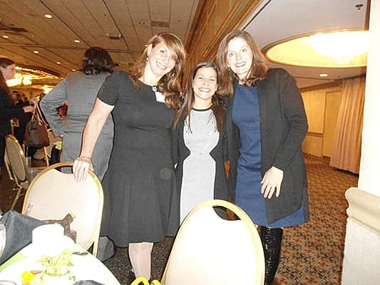 Three women smiling at a social event.
