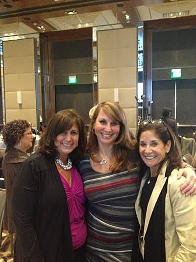 Three women smiling at an event.