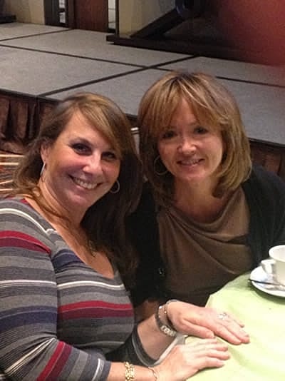 Two women smiling at a table together.