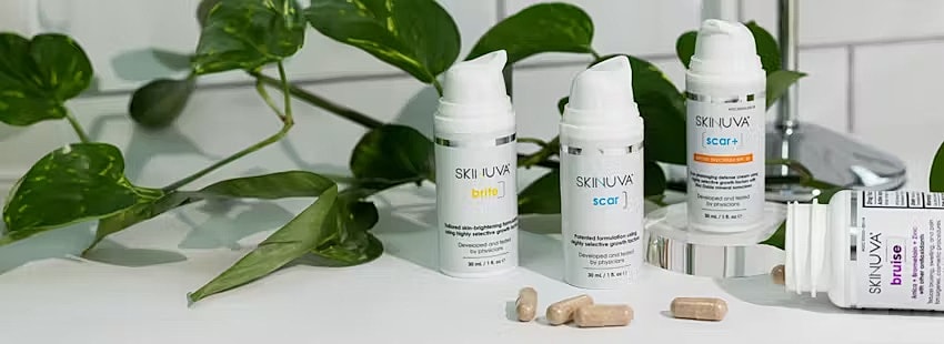 Skin care products on a countertop with greenery.