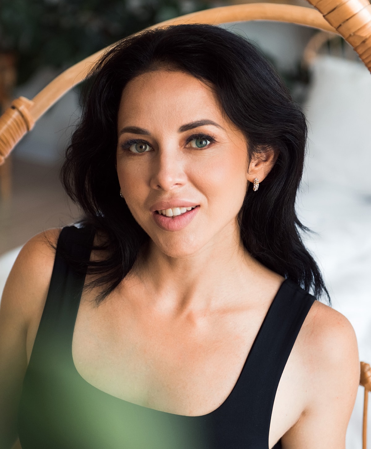 Woman smiling in natural light with lush background.
