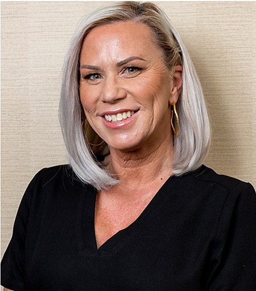 Smiling woman with short blonde hair, professional attire.