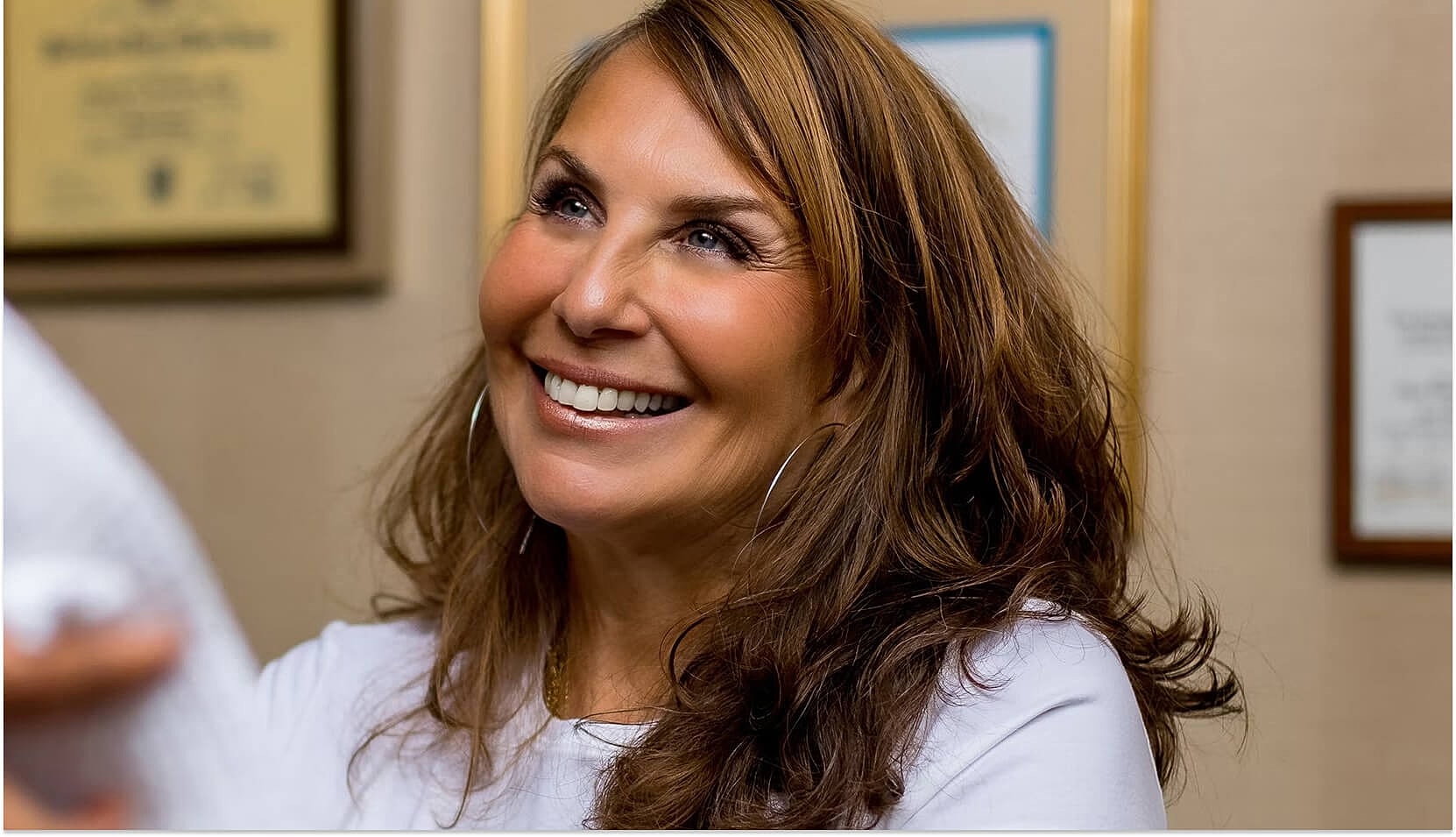 Smiling woman with long hair in an office setting.