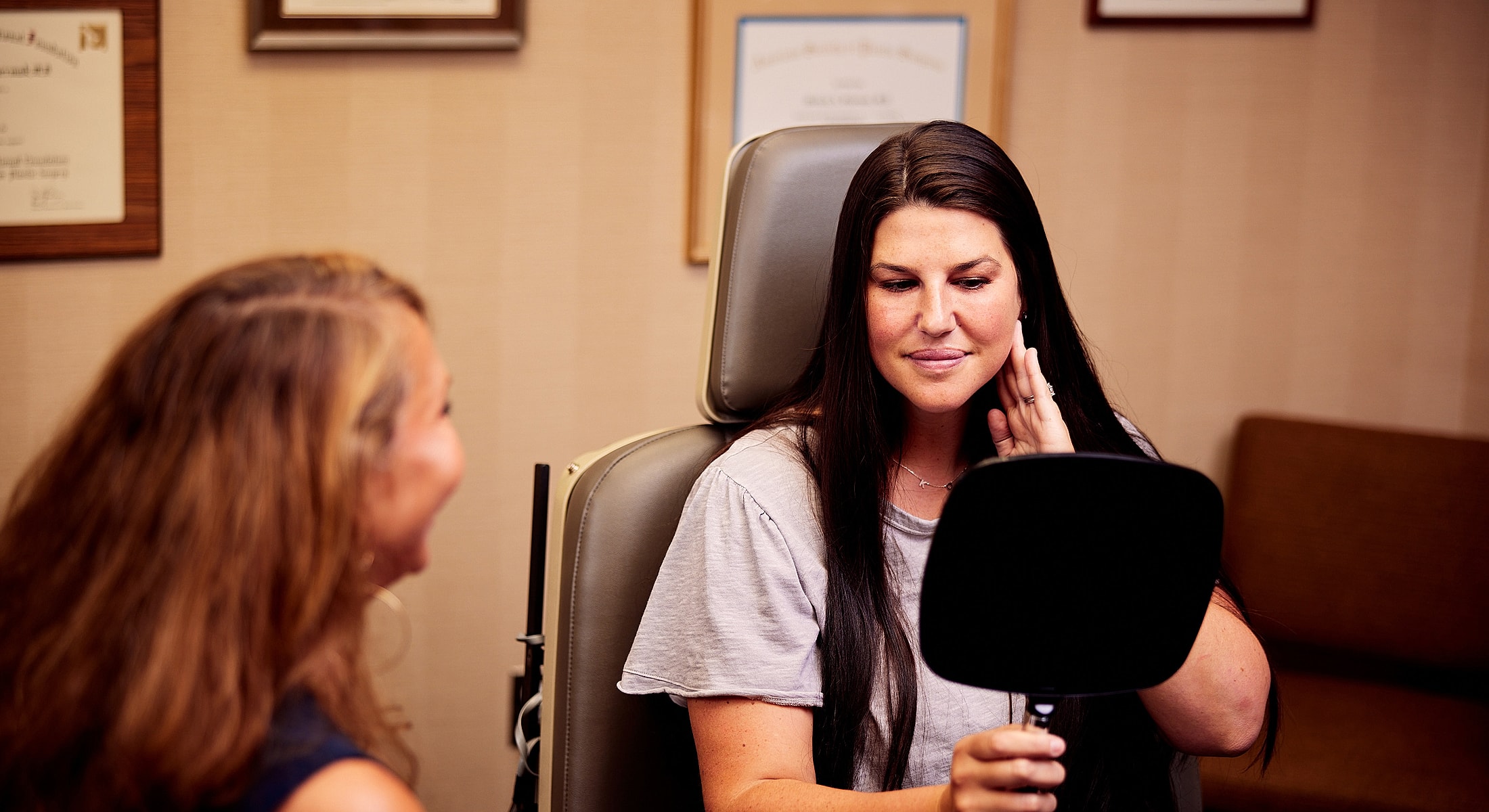 Woman examining her face in a mirror.